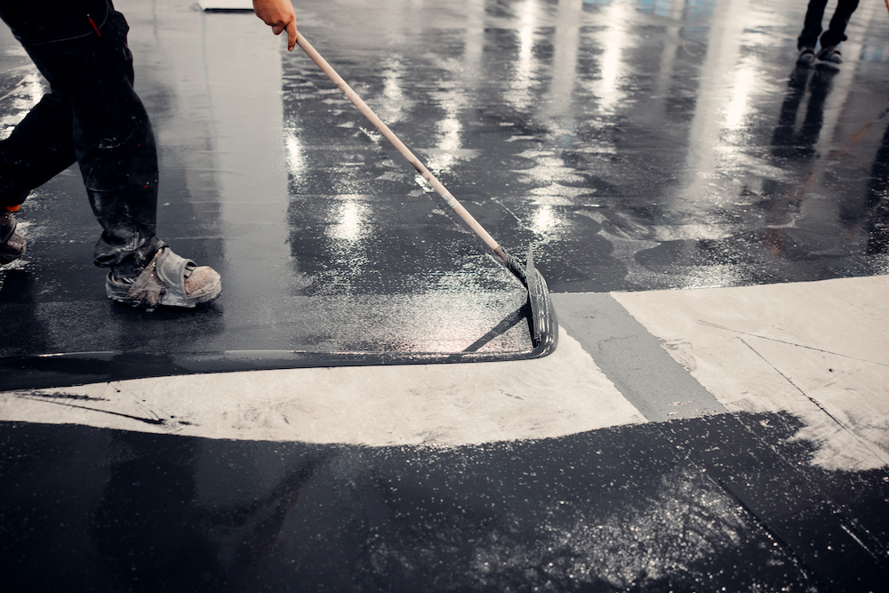 Worker applies gray epoxy reisin to a new floor. Modern Surface