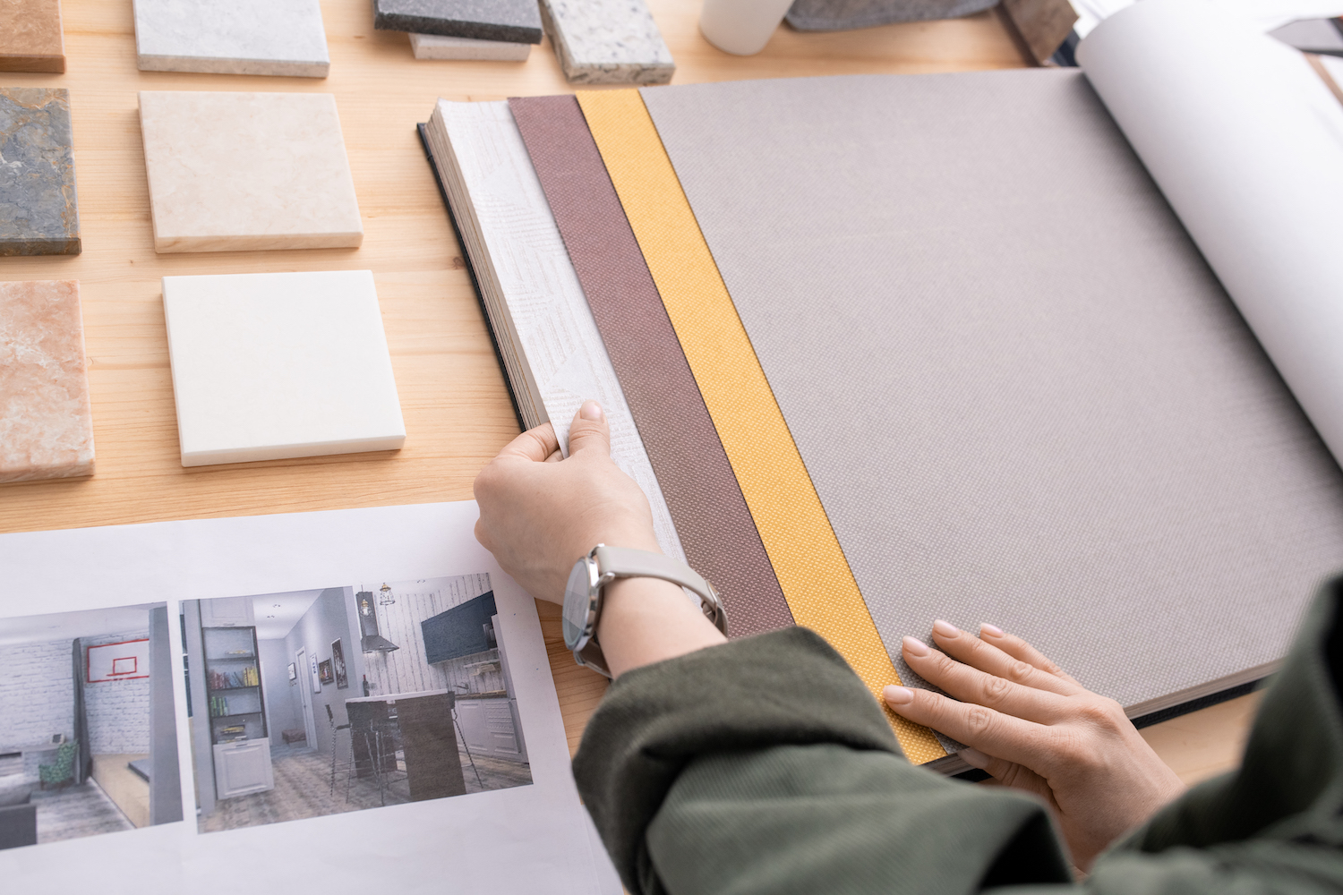 Hands of young contemporary designer looking through samples of wallpapers